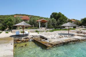 a pool of water with two chairs and umbrellas at House Zelanto Mali in Tkon