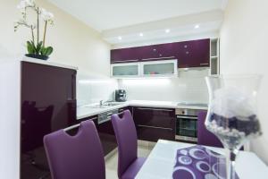 a kitchen with purple chairs and a table with a wine glass at Apartment Songbird in Biograd na Moru