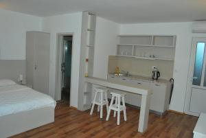 a bedroom with a bed and a kitchen with two stools at Hotel Art Media in Herceg-Novi