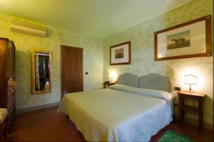 a hotel room with a bed and a lamp at Relais Poggio Borgoni in San Casciano in Val di Pesa
