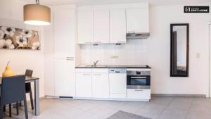 eine Küche mit weißen Schränken, einem Tisch und einem Waschbecken in der Unterkunft Quartier des Quais Dansaert in Brüssel