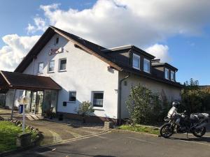 uma moto estacionada em frente a uma casa branca em Gästehaus Falkenstein em Niedenstein