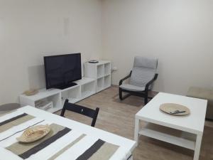 Una sala de estar con un televisor y una mesa y sillas. en Apartamentos Albeniz, en Algeciras