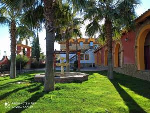 um quintal com palmeiras em frente a um edifício em Hotel Rural Romero Torres em Fuente Obejuna