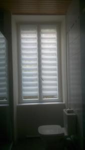 a bathroom with a toilet and a window with blinds at Chalet Bruyère in Cauterets +2 photos