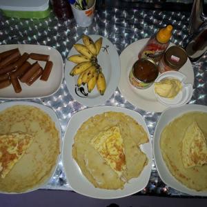 a table topped with plates of food with bananas and hot dogs at Mulu D Cave Homestay Room 2 in Mulu