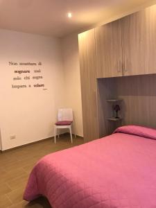 um quarto com uma cama rosa e uma cadeira em b&b pellipario em Urbino