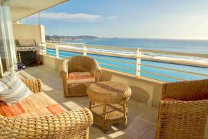 un balcón con sillas y mesas de mimbre y el océano en San Alfonso del Mar - Algarrobo 886, en Algarrobo