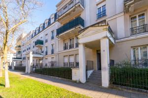 an apartment building with a fence in front of it at Family Travel Paris 3 in Bussy-Saint-Georges