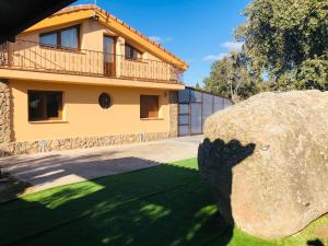 een huis met een grote rots ervoor bij Villa Encinas Piscina Climatizada in Ituero y Lama