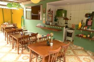 um restaurante com mesas e cadeiras de madeira e uma cozinha em Hostel MPB Ilha Grande em Abraão