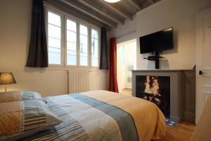 Schlafzimmer mit einem Bett, einem Kamin und einem TV in der Unterkunft Au bonheur d'Etretat in Étretat