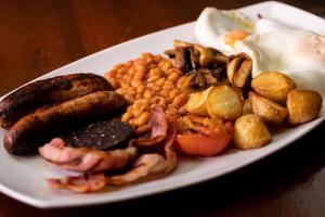 ein Frühstücksteller mit Würstchen, Bohnen und Eiern in der Unterkunft Radstock Hotel near Bath in Radstock