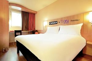 a hotel room with a large bed and two lamps at ibis Beauvais Aéroport in Beauvais