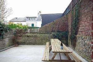 una bottiglia di vino seduta su una panchina di legno accanto a un muro di mattoni di Au bonheur d'Etretat a Étretat