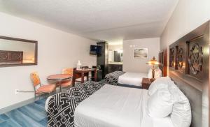 een hotelkamer met 2 bedden en een tafel bij Sunshine Inn in Kissimmee