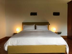 a bedroom with a large white bed with two lamps at La VIGIE de CASTELROCK ( Casa Petunia ) in Mosteiros