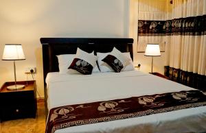 a bedroom with a large bed with two lamps at SUNSET HILLS in Kandy