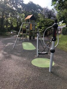 um parque infantil com escorrega e um baloiço em Trail Lodge em Ballasalla