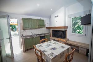 a kitchen with green cabinets and a table with chairs at Appartamenti & Bungalows Luca Angiolin in Cavallino-Treporti