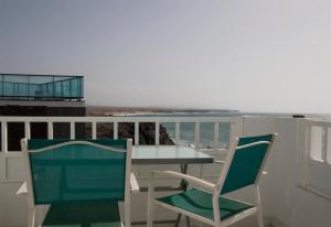 two chairs and a table on a balcony with the ocean at Apartamentos Juan Benítez in El Cotillo