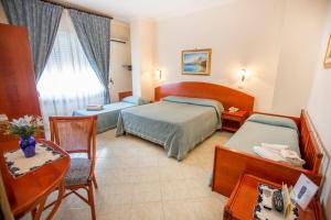 pokój hotelowy z 2 łóżkami i stołem w obiekcie Hotel Mediterraneo w Cefalù