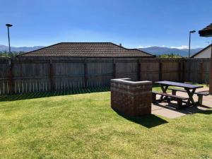 a picnic table in a yard with a fence at Blaeberry Cottage in Aviemore +19 photos