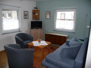 een woonkamer met een bank, stoelen en een tafel bij Ferienwohnung Ambiente in Winterberg