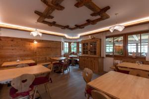 um restaurante com mesas e cadeiras de madeira e janelas em Agriturismo Maso Corradini em Castello di Fiemme