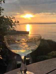 a wine glass sitting on a table with a sunset in the background at Perfect getaway, seafront home in Bangor