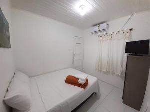 a small white room with a bed and a television at Hotel Pousada Villa Calhau in São Luís