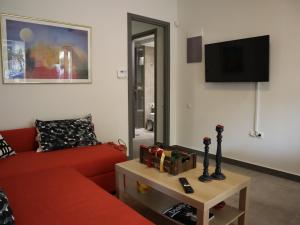 uma sala de estar com um sofá vermelho e uma televisão em Nefeli em Atenas