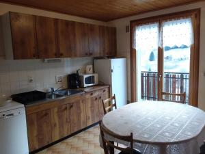 a kitchen with a table and a refrigerator and a table with chairs at Le Fayet d'en haut in Abondance