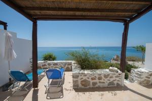 eine Terrasse mit blauen Stühlen und Meerblick in der Unterkunft Kionia Apartments in Kerames