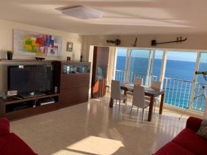 a living room with a television and a table and chairs at Apartamento en primera línea de mar, 8 personas in Platja d'Aro