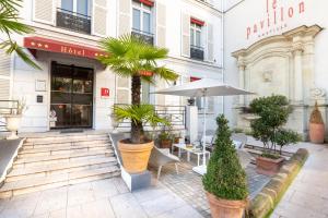 パリにあるオテル パヴィヨン バスティーユの植物と傘が備わるパティオ付きのホテル