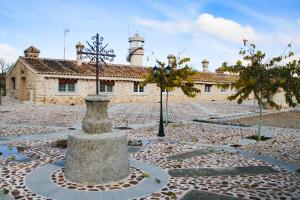 una iglesia con una cruz frente a un edificio en Casas rurales Puente Romano en Sonseca