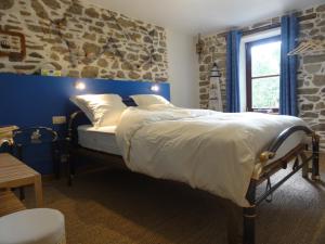 una camera da letto con un letto con un muro di pietra di Chambres d'Hôtes du Moulin de Brendaouez a Guissény