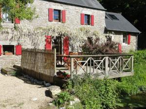 GuissényにあるChambres d'Hôtes du Moulin de Brendaouezの赤い襖と木の柵のある石造りの家