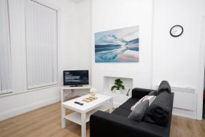 a living room with a black couch and a tv at KIRKSTALL SERVICED APARTMENTS LEEDS in Leeds