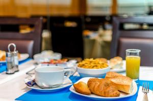 - une table avec des assiettes de nourriture et une tasse de jus d'orange dans l'établissement Helgon Hotel - Lourdes Pyrénées, à Lourdes