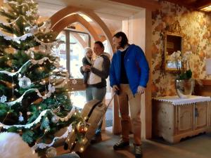 a man and a woman standing next to a christmas tree at Alpenhotel La Montanara in Rocca Pietore