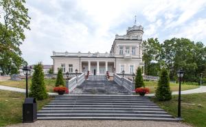 a large white building with stairs in front at Relax apartments near Egle in Druskininkai