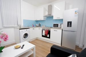 a kitchen with white appliances and a white table at KIRKSTALL SERVICED APARTMENTS LEEDS in Leeds