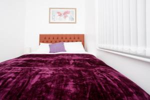 Un dormitorio con una manta morada en una cama en KIRKSTALL SERVICED APARTMENTS LEEDS en Leeds
