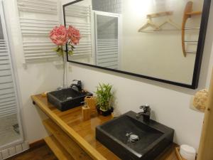 un bagno con 2 lavandini neri e uno specchio di Chambres d'Hôtes du Moulin de Brendaouez a Guissény