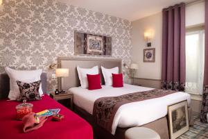 a hotel room with two beds with red pillows at Hotel Monceau Wagram in Paris +66 photos