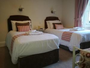 Lubnaig Guest House في كالالندر: غرفة نوم بسريرين مع شراشف بيضاء