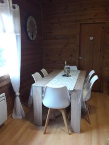 une table à manger avec des chaises blanches et une horloge dans l'établissement chalet "le Refuge du Brabant", à Cornimont