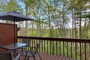 a table and chairs on a deck with an umbrella at LAKE GEORGE FAMILY VACATION HOME in Lake George